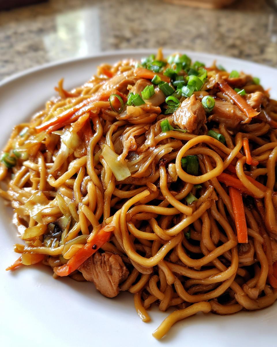 Close-up of a serving of homemade chicken chow mein recipe, topped with fresh green onions.