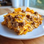 A close-up serving of rich Dorito Casserole layered with seasoned ground beef and melted cheddar cheese.
