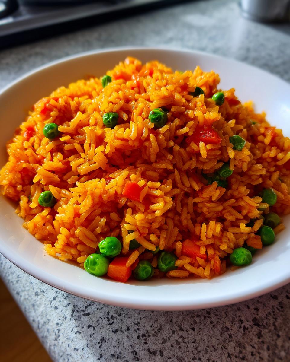 Close-up of fluffy, vibrant orange spanish rice mixed with bright green peas and diced carrots in a white bowl.