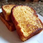 Close-up of three golden brown slices of easy french toast stacked on a white plate.