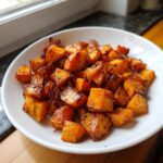 A bowl filled with caramelized, perfectly seasoned roasted sweet potato cubes.
