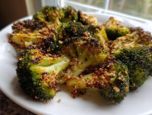 Close-up of perfectly cooked roasted broccoli florets with crispy, browned edges served on a white plate.