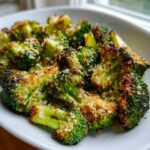 Close-up of perfectly roasted broccoli florets topped with crispy Parmesan cheese.