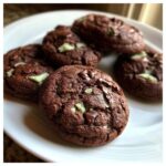 Five rich, fudgy chocolate Andes Mint cookies studded with mint chips, resting on a white plate.