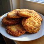 A stack of freshly baked brown butter sugar cookies generously coated in sparkling cinnamon sugar on a white plate.
