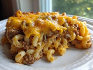 A close-up serving of cheesy cheeseburger casserole featuring ground beef, elbow macaroni, and melted cheddar cheese.