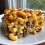 Close-up of a hearty square serving of cheeseburger casserole featuring elbow macaroni, ground beef, and melted, browned cheese.