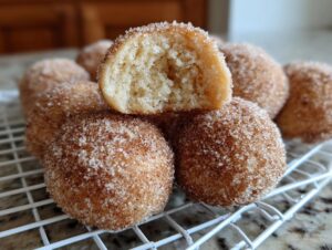 A pile of freshly made cinnamon sugar snowball cookies, with one cookie broken in half showing the soft interior.