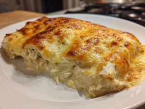Close-up of a serving of white chicken enchiladas covered in melted, golden-brown cheese.