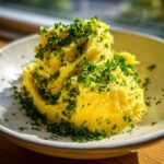 A mound of bright yellow, fluffy garlic butter generously topped with finely chopped green parsley.