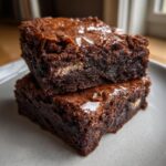 Two stacked, fudgy Oreo brownies showing a shiny top crust and a hint of white filling inside.