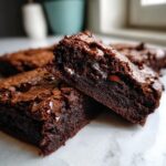 Close-up of two fudgy sweet potato brownies stacked, showing melted chocolate chips inside.