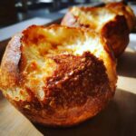 Close-up of two freshly baked, hollowed-out bread bowls with a deep golden, crusty exterior.