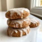 A stack of three thick maple brown sugar cookies topped with a sweet white glaze dripping down the sides.