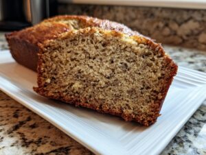 Close-up of a thick slice cut from a loaf of moist banana bread recipe, showing the texture.