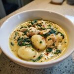 Close-up of a white bowl filled with creamy olive garden chicken gnocchi soup, featuring tender chicken, soft gnocchi, and spinach.