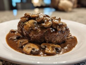 A close-up of a perfectly cooked Salisbury steak smothered in rich brown mushroom gravy.