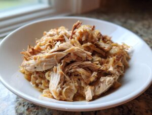 Close-up of tender, shredded pork and sauerkraut mixture served in a white bowl.