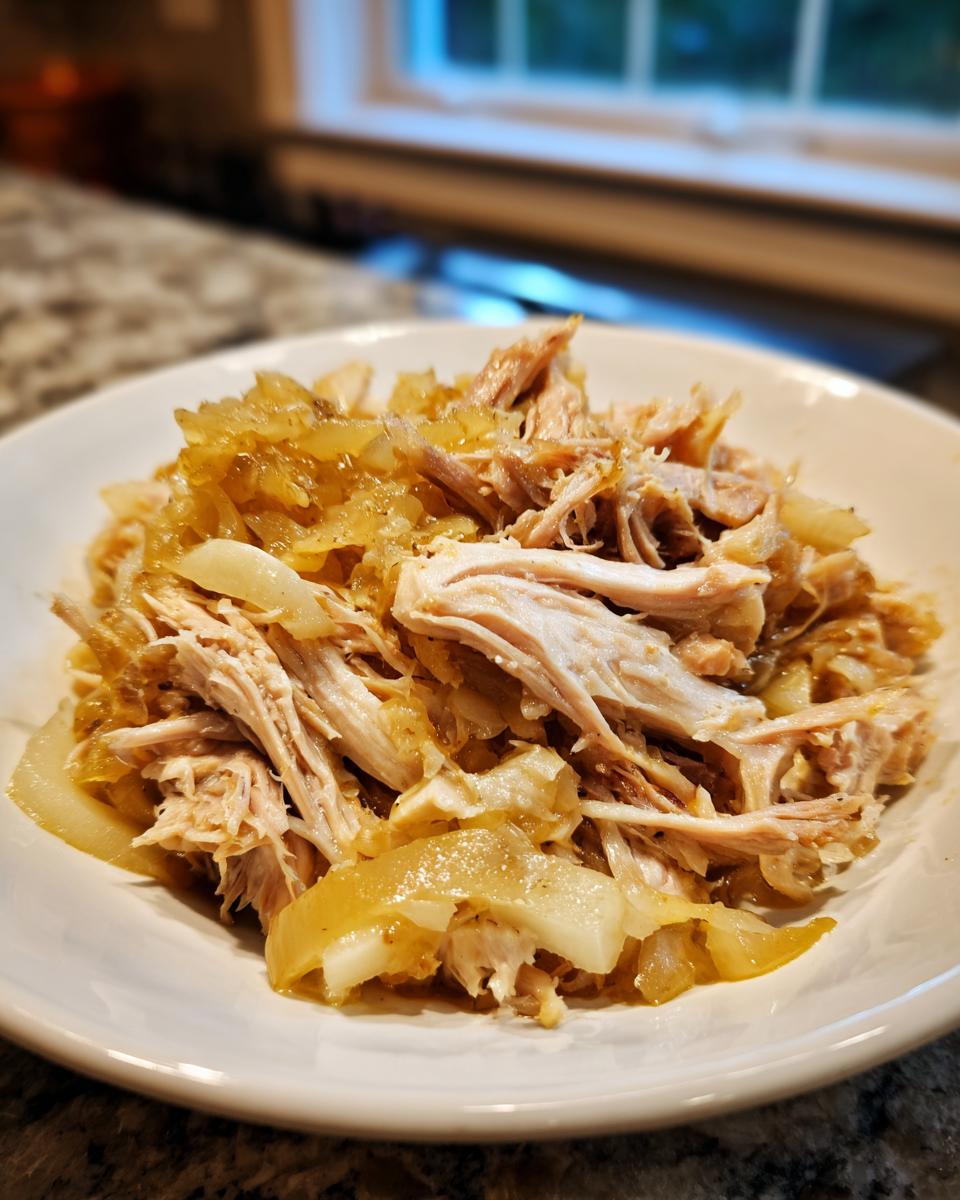 Close-up of tender, shredded pork mixed with caramelized onions and sauerkraut, ready to eat.