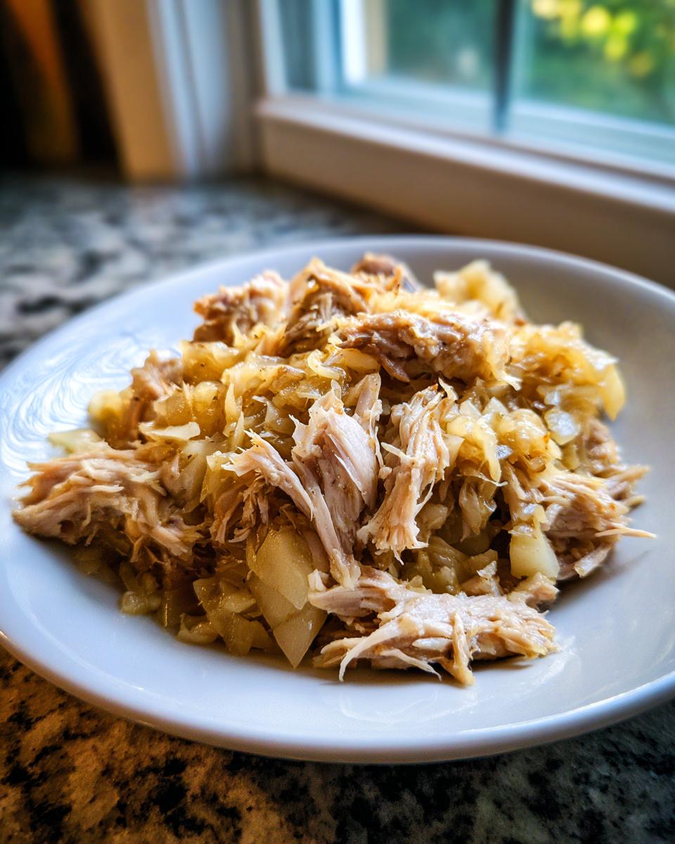Close-up of shredded pork and sauerkraut mixture served on a white plate.