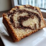 Close-up of a moist slice of cinnamon bread featuring a beautiful swirl pattern of light vanilla cake and dark cinnamon filling.