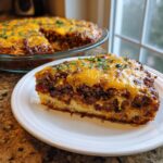 A thick slice of layered Texas Trash Dip featuring a base, meat filling, and melted cheddar cheese topping, garnished with parsley.