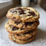 A tempting stack of five chewy chocolate chip cookies topped with large chocolate chunks and sea salt.