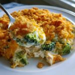 A spoonful of creamy Chicken Divan casserole featuring broccoli florets, shredded chicken, and a crunchy golden topping.