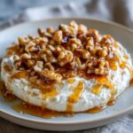 Close-up of a creamy whipped ricotta dip topped generously with candied walnuts and drizzled with honey.
